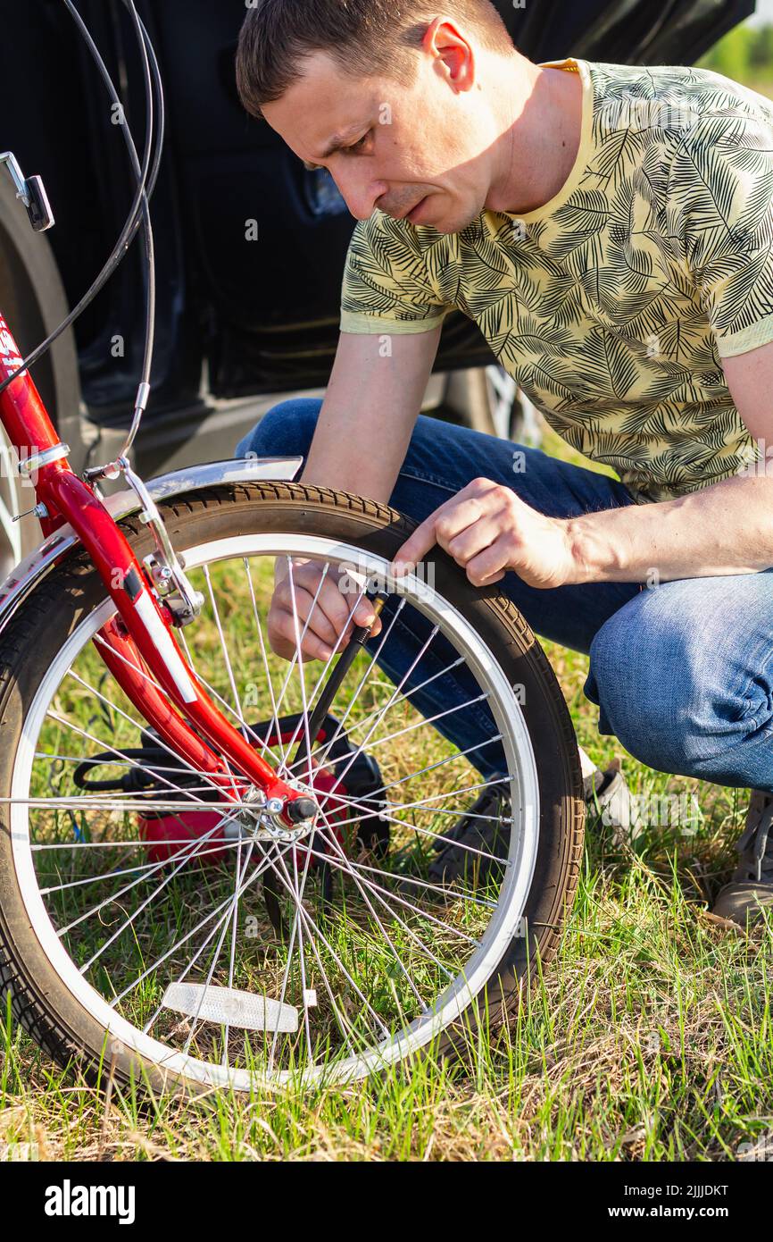 Papa pumpt Fahrradreifen für seine Tochter hoch. Nahaufnahme Handsome Bike Mechanic pumpt Fahrrad Rad. Weltfahrradtag. Konzept Zur Fahrradwartung. Techn Stockfoto