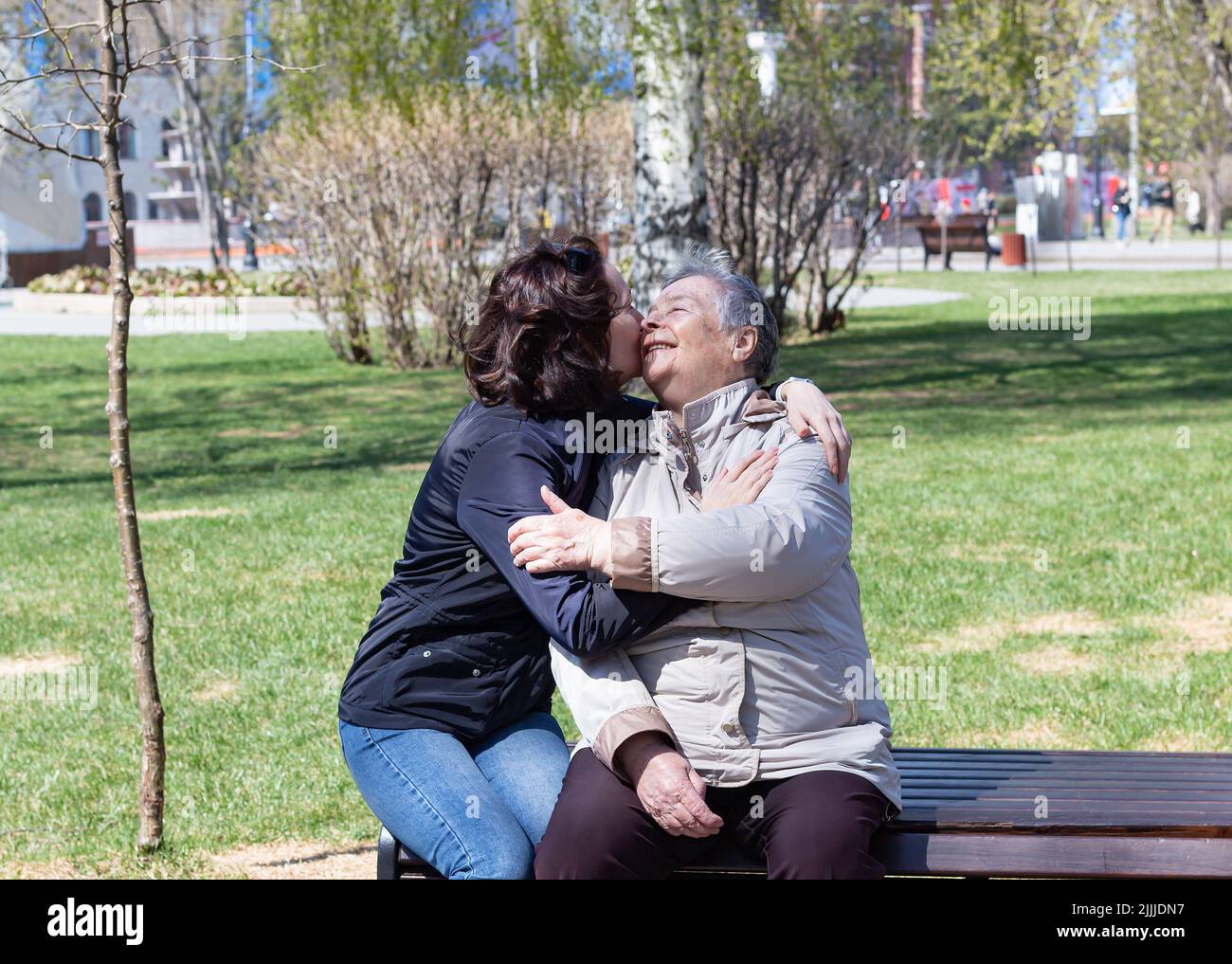 Portrait von zwei hübschen lächelnden Frauen, die sich umarmen und küssen und sich glücklich treffen. Selektiver Fokus, Großeltern-Tag, Muttertag, Weltbevölkerung Stockfoto