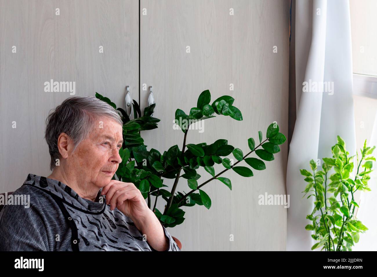 Ältere pensionierte Frau sitzt auf der Veranda in Depression, Einsamkeit. Ältere Frau wartet, mit Kopieplatz, selektiver Fokus.globaler Tag der Eltern Stockfoto