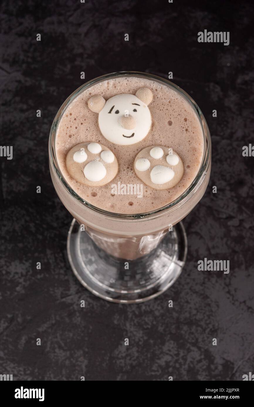 In einem Café auf dunklem Hintergrund ist ein Kakaogetränk mit lustigen Keksen dekoriert Stockfoto