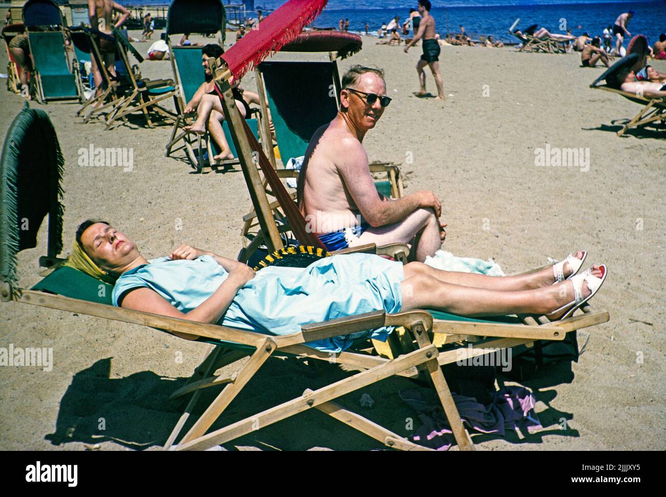 Sonnenbaden in Liegestühlen am Sandstrand am Mittelmeer, Barcelona, Katalonien, Spanien Juli 1958 Stockfoto