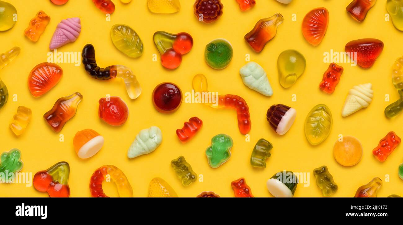 Nahtloses Muster aus verschiedenen Gelee-Gummi-Fruchtbonbons auf gelbem Hintergrund Draufsicht flach legen Stockfoto