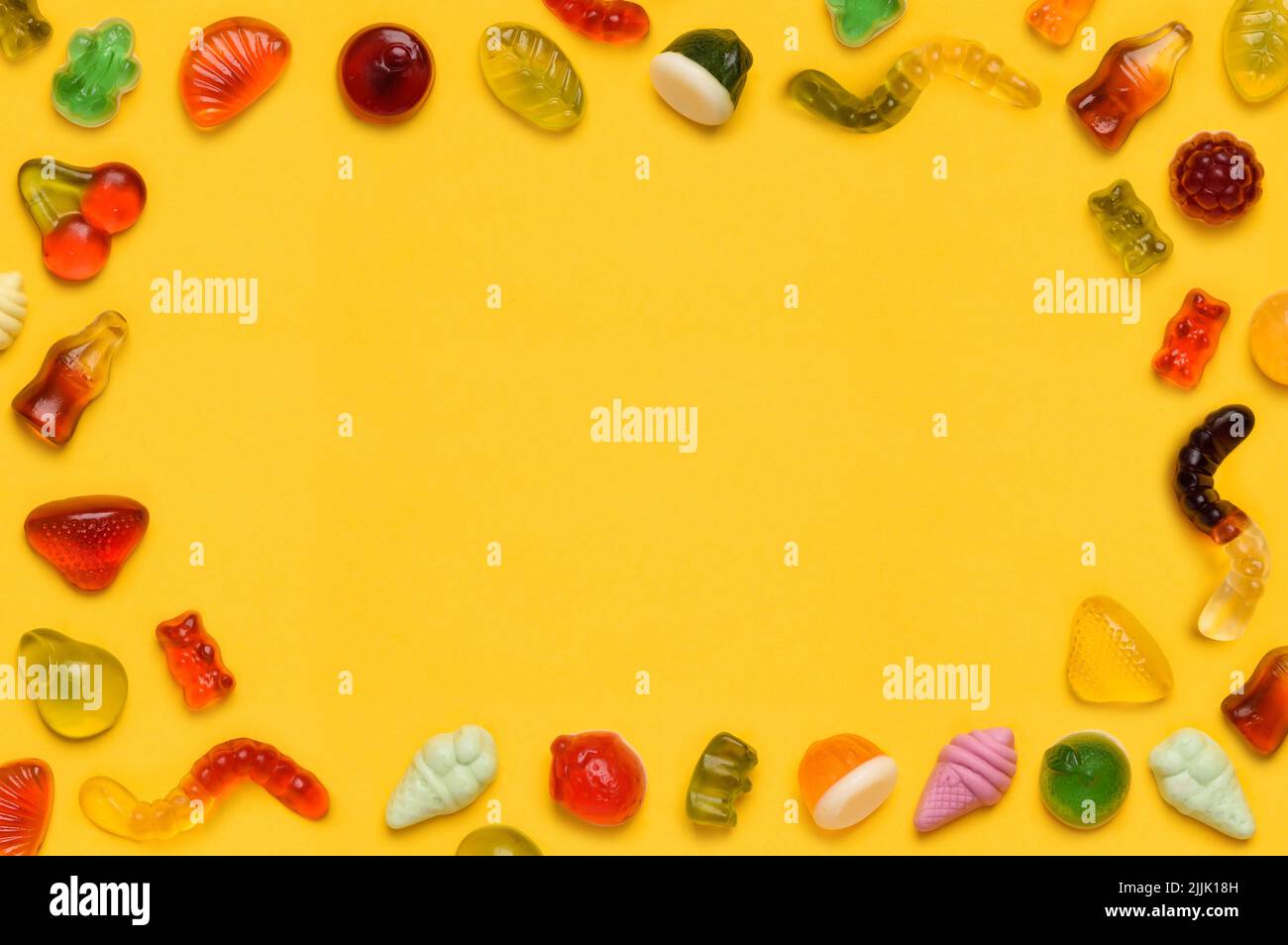 Gummy Candy Rahmen Rand, verschiedene Gelee Gummi Obst Süßigkeiten Süßigkeiten auf gelbem Hintergrund Draufsicht flach legen Stockfoto