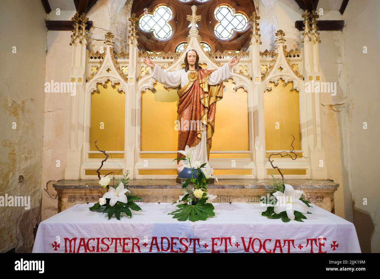 Ein Seitenaltar mit einer großen Statue von Jesus, die eine rote und goldene Robe mit einem Herz auf seiner Brust trägt. In der Metropolitan Cathedral in Cardiff, Wales, United K Stockfoto