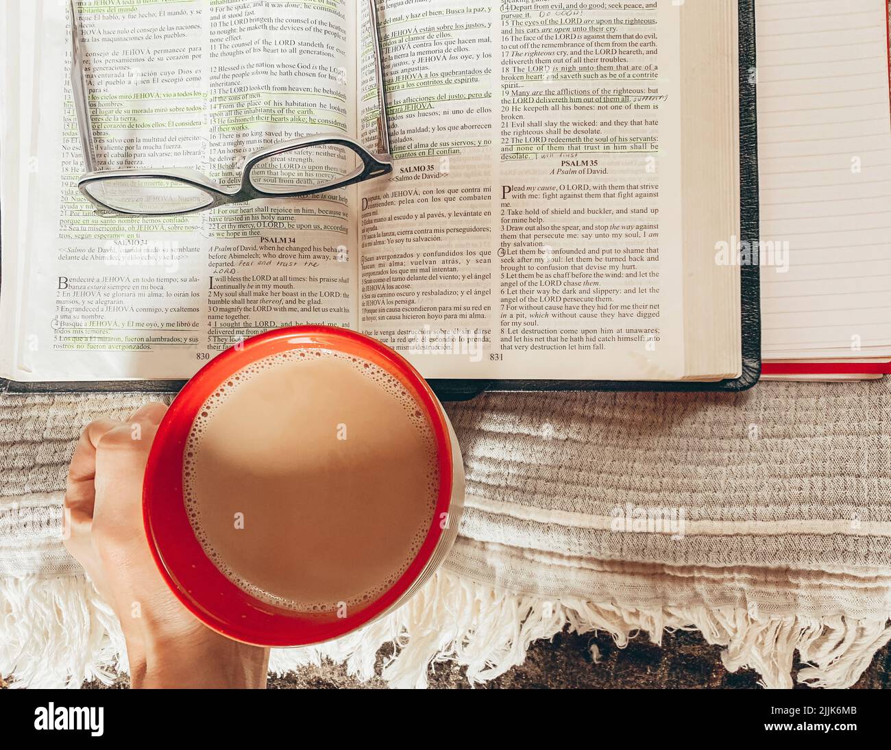 Ein religiöses Buch mit Gläsern darauf neben einer Tasse Stockfoto