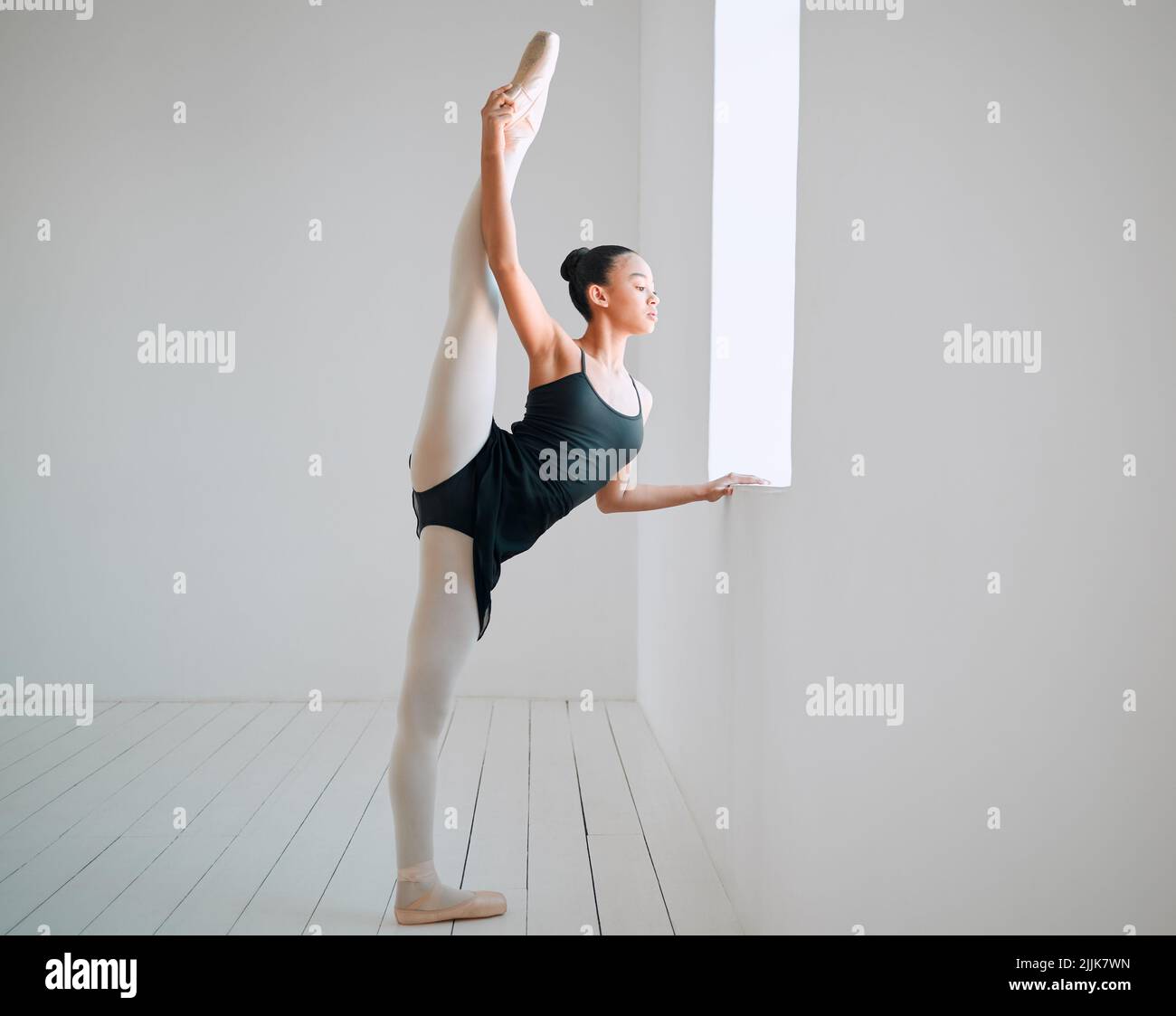 Klassischer Tanz ist eine schöne Form der Kommunikation. Ganzkörperaufnahme einer attraktiven jungen Ballerina, die in ihrem Tanzstudio praktiziert. Stockfoto