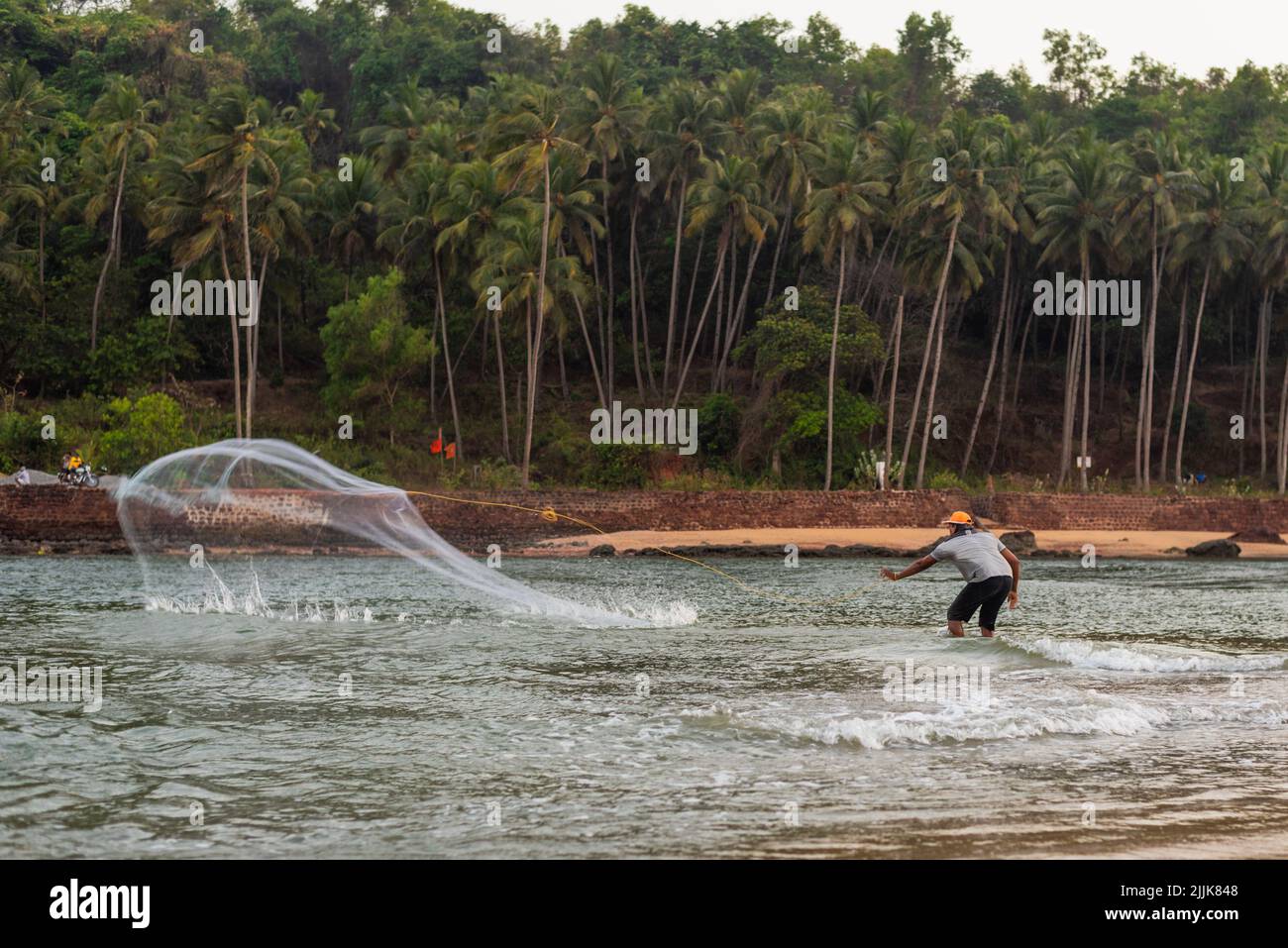 Ein indischer Fischer, der das Netz im Dorf Betul, Salcete, Goa, Indien, in den Ozean wirft Stockfoto