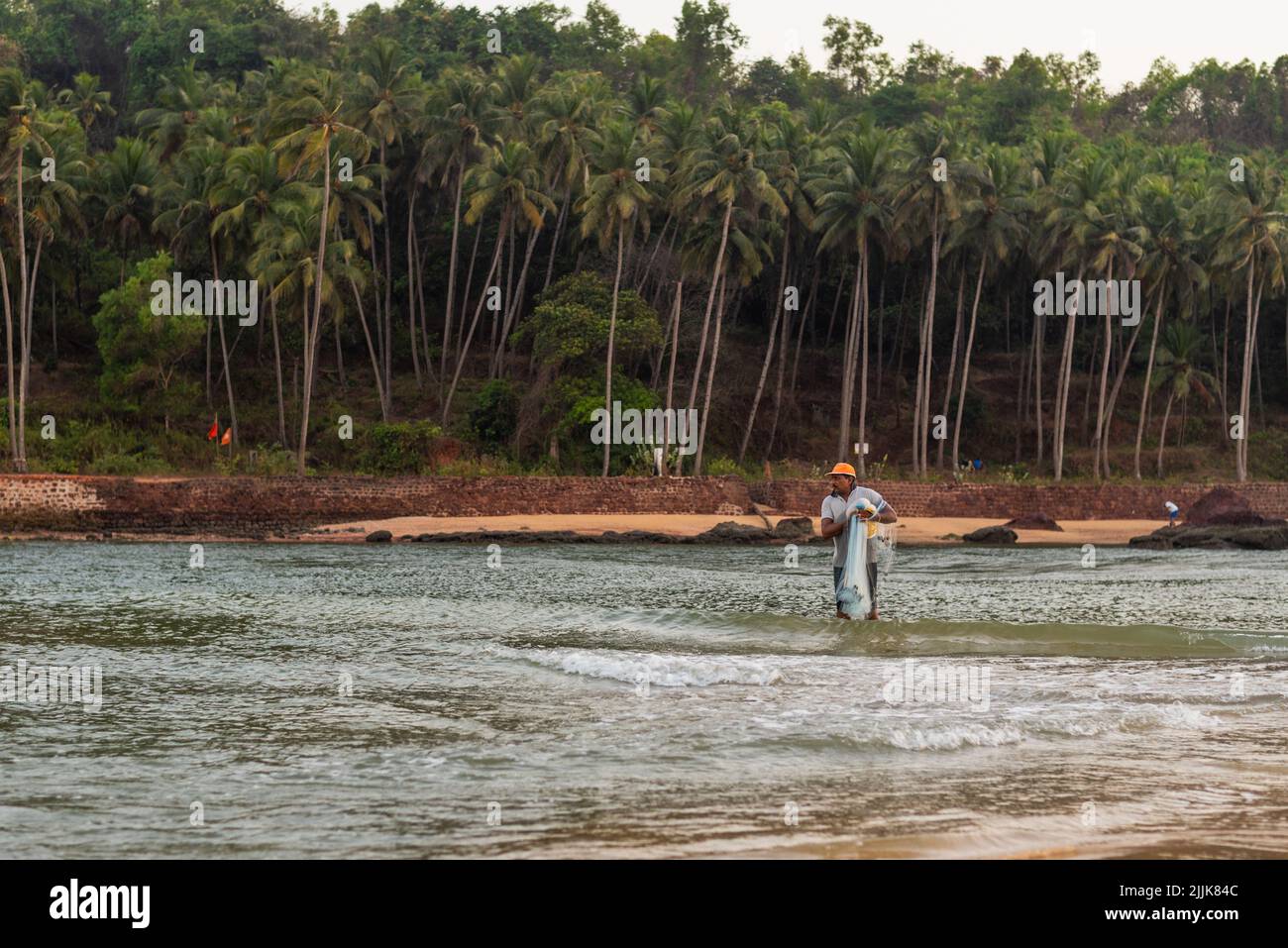 Ein indischer Fischer, der das Netz im Dorf Betul, Salcete, Goa, Indien, in den Ozean wirft Stockfoto