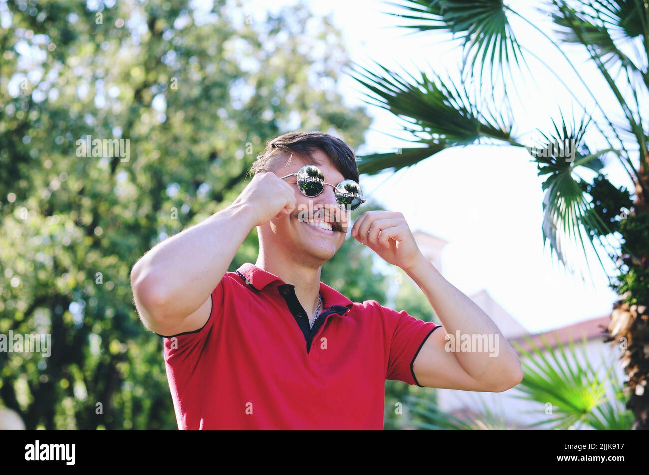 Junger glücklicher, gutaussehender bärtiger Mann, Tourist, der in der Altstadt von Koper spazieren geht. Sommerurlaub. Sonnenbrille. Lifestyle-Porträt Stockfoto