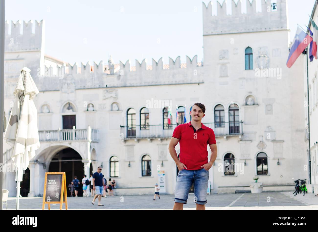 Junger glücklicher, gutaussehender bärtiger Mann, Tourist, der in der Altstadt von Koper spazieren geht. Sommerurlaub. Sonnenbrille. Lifestyle-Porträt Stockfoto