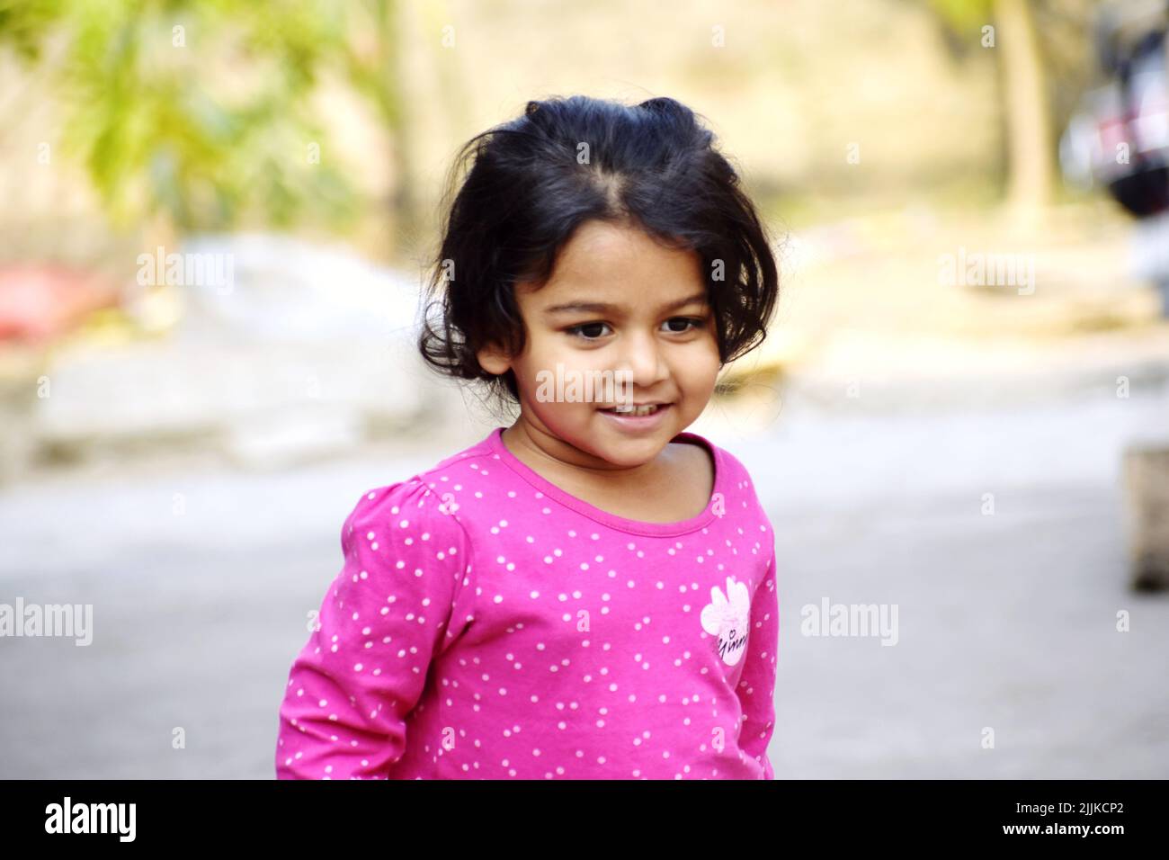 Ein indisches schwarzhaariges Mädchen, das lächelt und im Park spielt Stockfoto