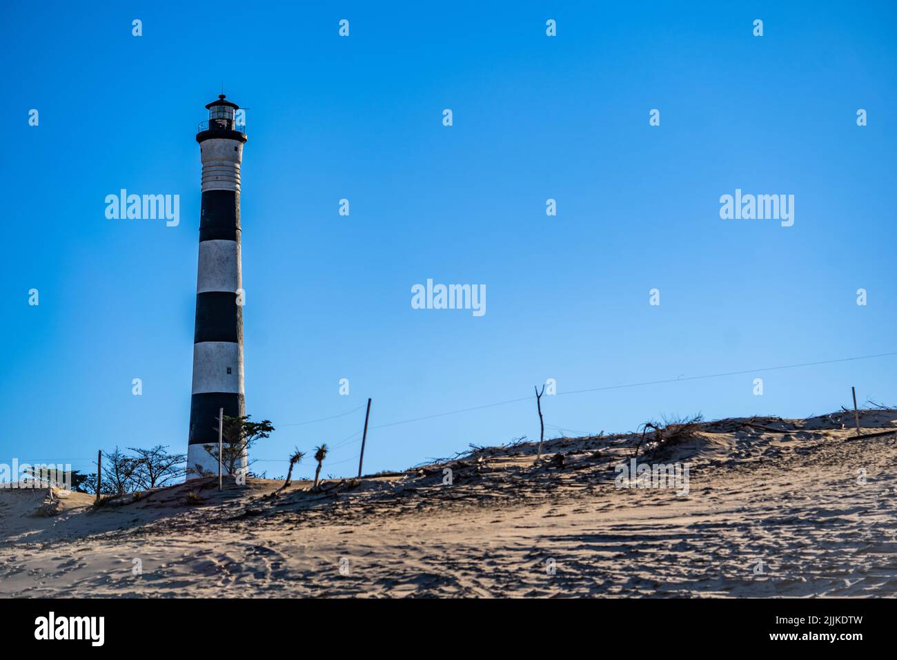 Frontansicht eines Leuchtturms am Strand, an einem sonnigen Tag mit einem klaren blauen Himmel Stockfoto