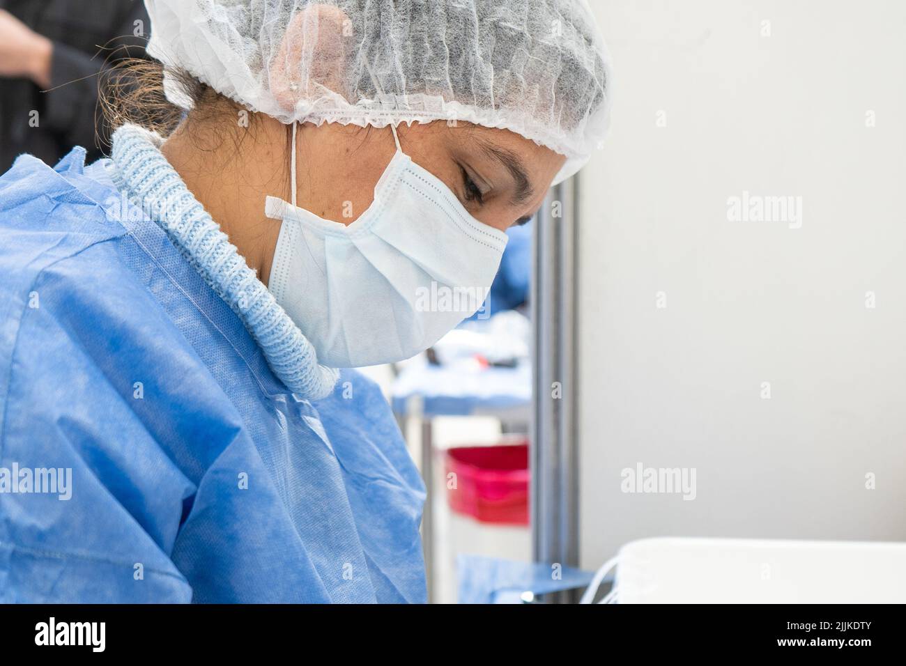 Krankenschwester im Profil mit Kappe und Maske, die jemanden gegen Covid 19 impfen will Stockfoto