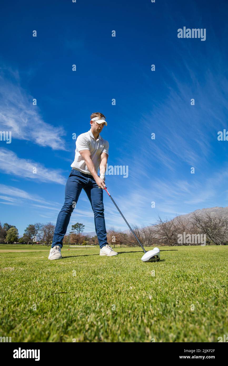 Eine vertikale Aufnahme eines kaukasischen Golfspielers, der einen Chip-Schuss auf einem Golfplatz spielt Stockfoto