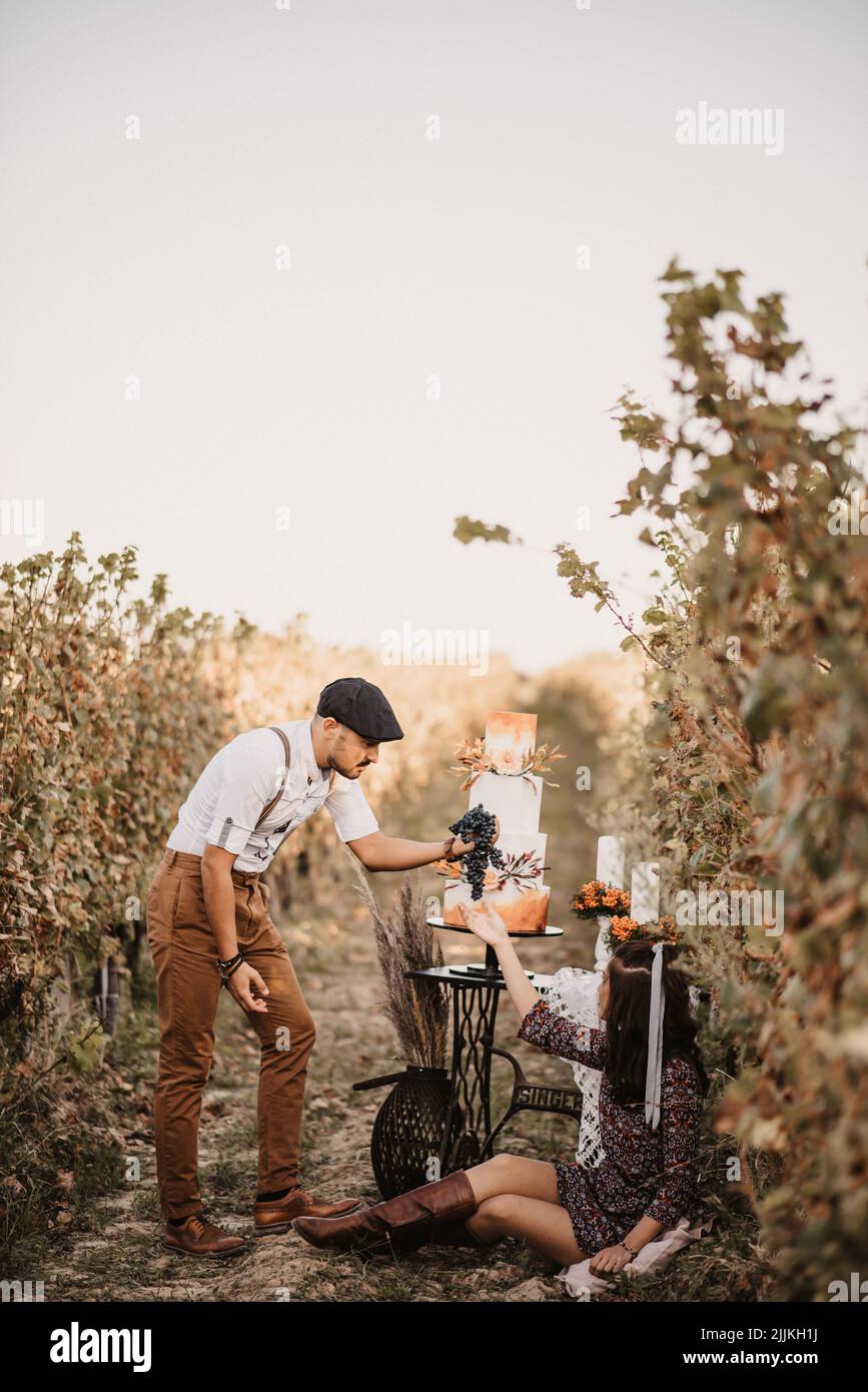 Eine vertikale Aufnahme eines kaukasischen Paares mit einem Verlobungsfoto in einem Weinberg Stockfoto