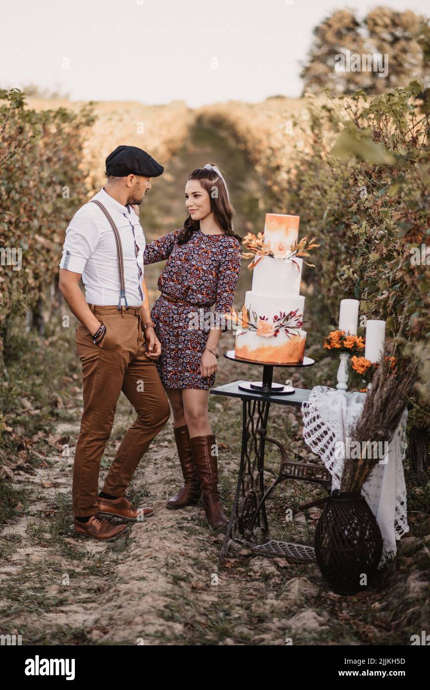 Eine vertikale Aufnahme eines kaukasischen Paares mit einem Verlobungsfoto in einem Weinberg Stockfoto