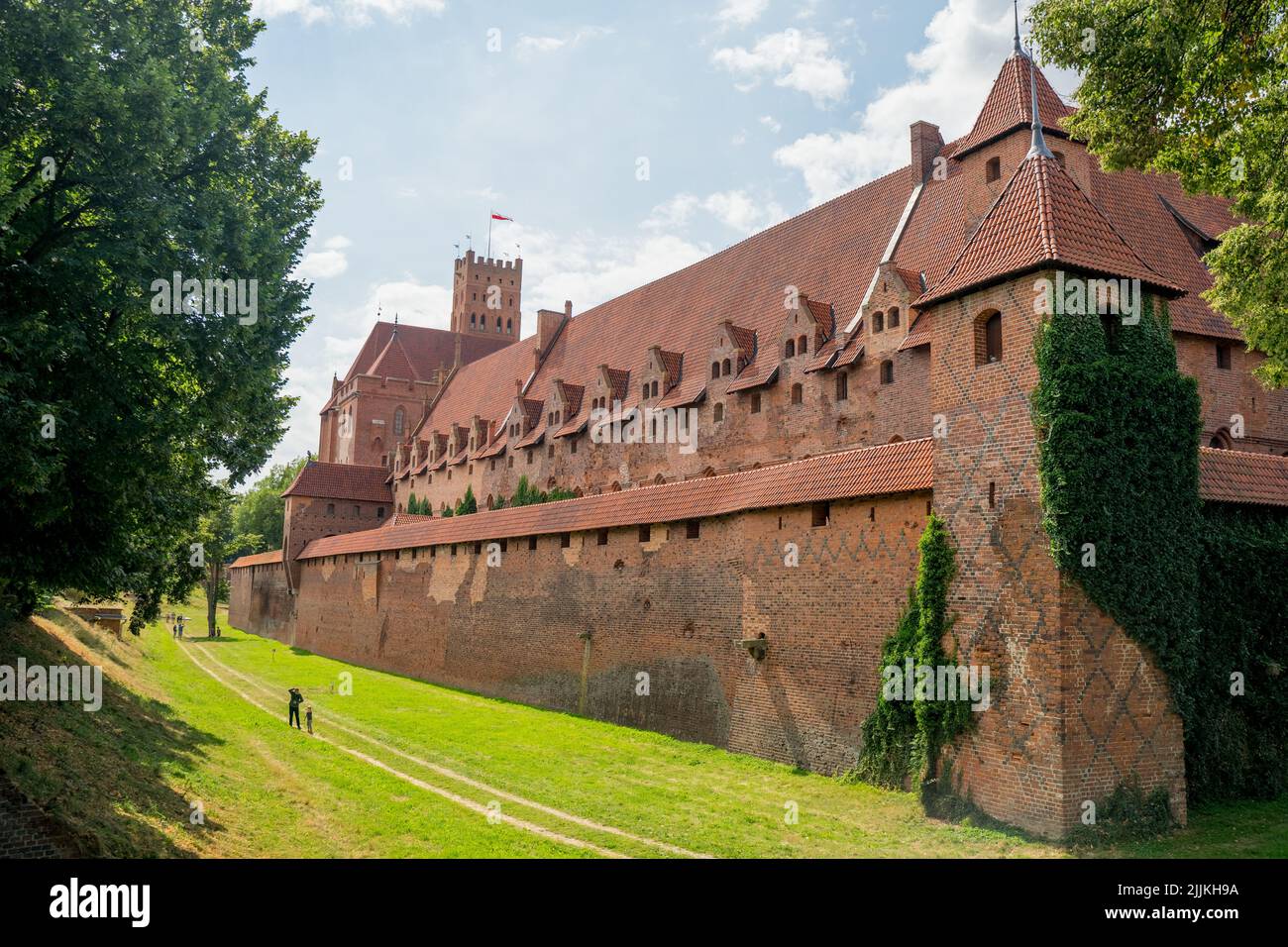 Eine schöne Außenansicht der Mauern des Schlosses in Malbork, Polen mit Grasland gegen einen blau bewölkten Himmel Stockfoto