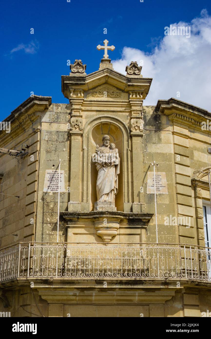 Eine vertikale Aufnahme einer Skulptur an der Ecke einer Kirche auf der Insel Gozo, Malta Stockfoto