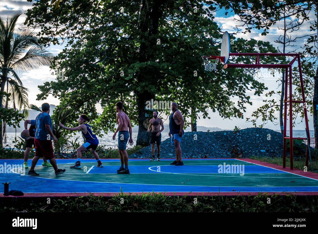 Eine Aufnahme einer Gruppe von Menschen, die in Costa Rica gegen eine Meereslandschaft Basketball spielen Stockfoto