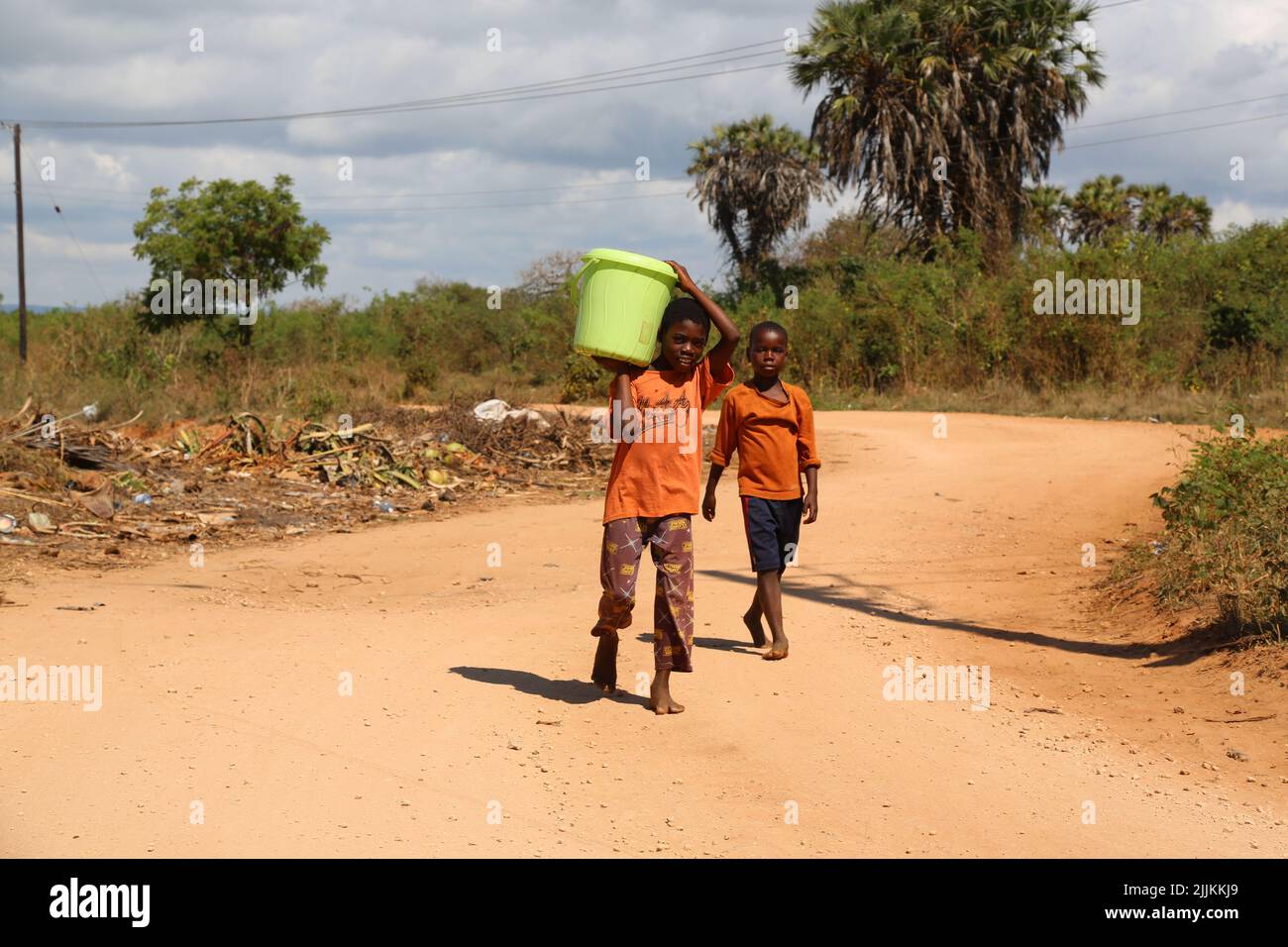 Die Kinder vor Ort, die Wasser mit Eimern in Ukunda, Kenia, tragen Stockfoto