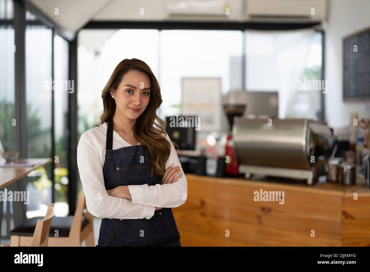 Coffee Business Owner Concept - attraktiver junger, schöner asiatischer Barista mit Schürze an der Theke des Cafés. Stockfoto