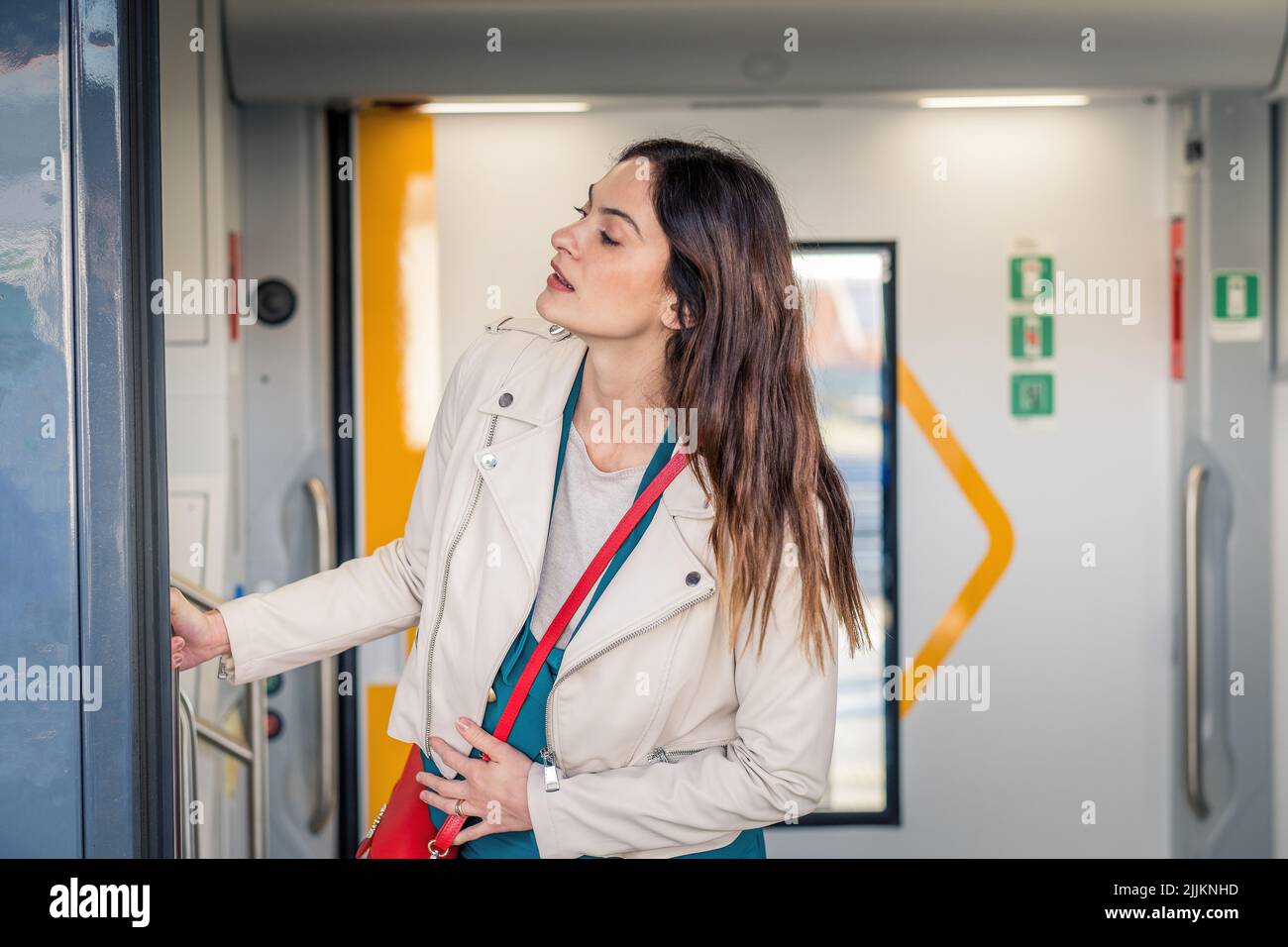 Es ist ein schönes Hotel, das eine Frau aus dem Zug fährt, die lächelt - eine junge Geschäftsfrau, die aus der Tür des Zuges guckt und jemanden sieht Stockfoto