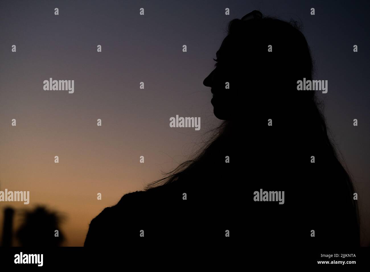 Selektiver Fokus der Silhouette eines Mädchens, das im Profil sitzt und den Sonnenuntergang betrachtet Stockfoto