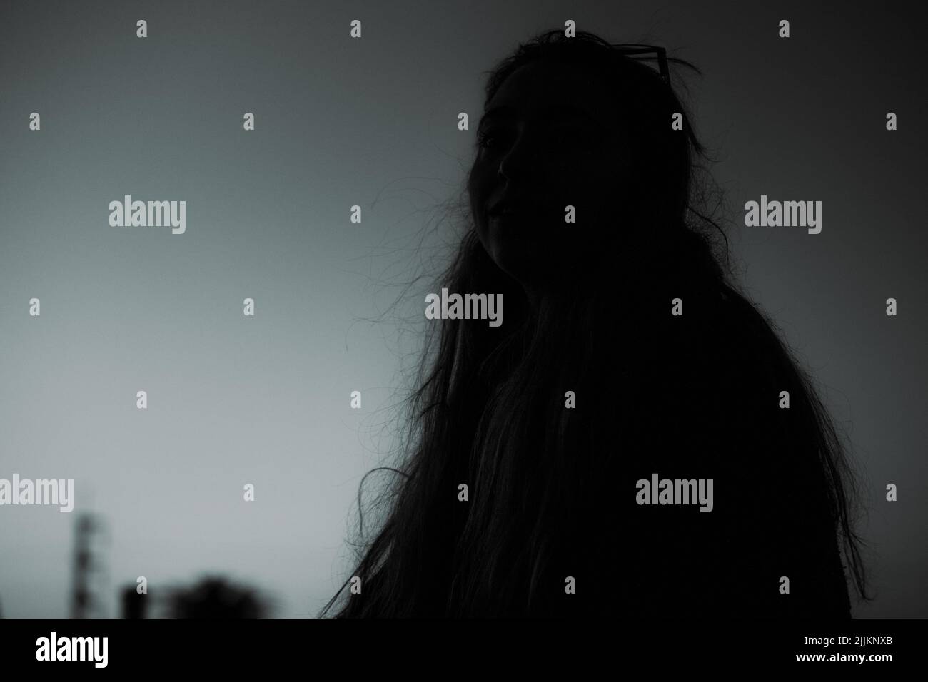 Selektiver Fokus der Silhouette eines Mädchens mit langen, lockeren Haaren mit dem Himmel im Hintergrund Stockfoto