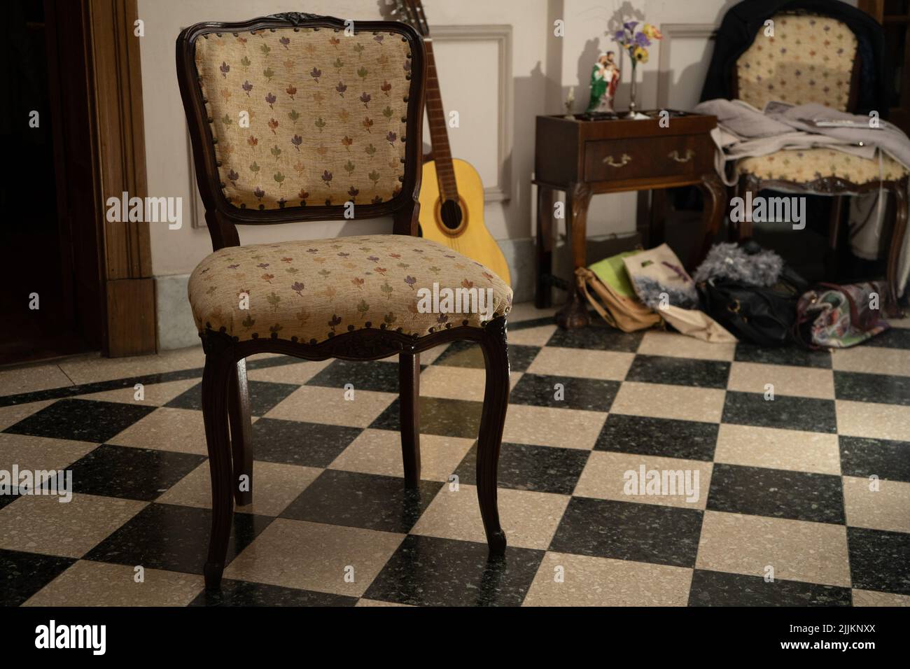 Selektiver Fokus eines Stuhls mit einer Gitarre dahinter im Esszimmer eines Hauses Stockfoto