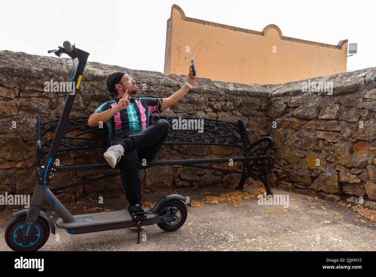 Der junge Mann mit Zöpfen nimmt ein Selfie mit seinem Elektroroller Stockfoto
