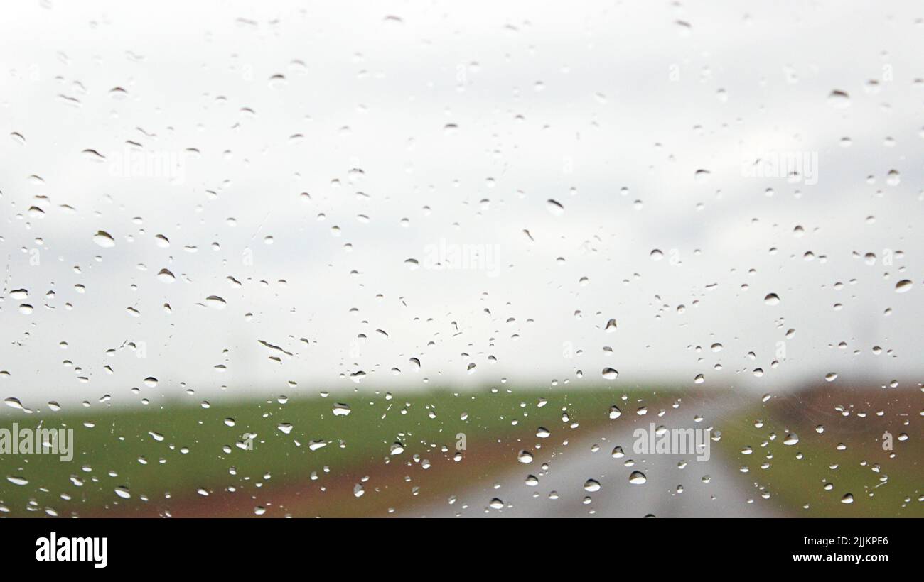 Blick auf die Straße durch das nasse Autoglas-Fenster Stockfoto