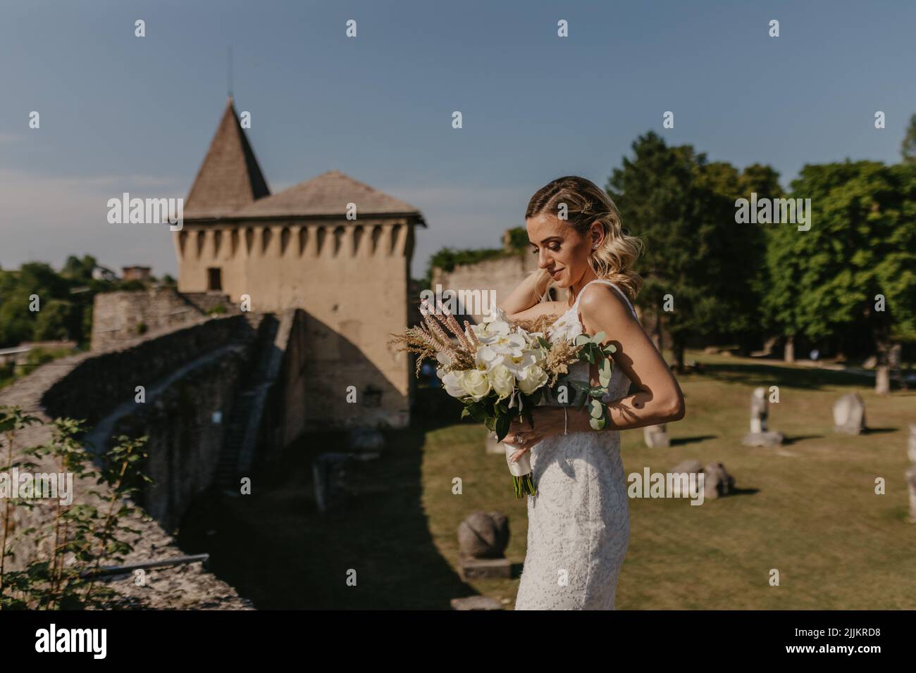 Eine Braut aus dem Nahen Osten mit einem Blumenstrauß im Hintergrund der Burg Ostrozac in Bosnien und Herzegowina. Stockfoto