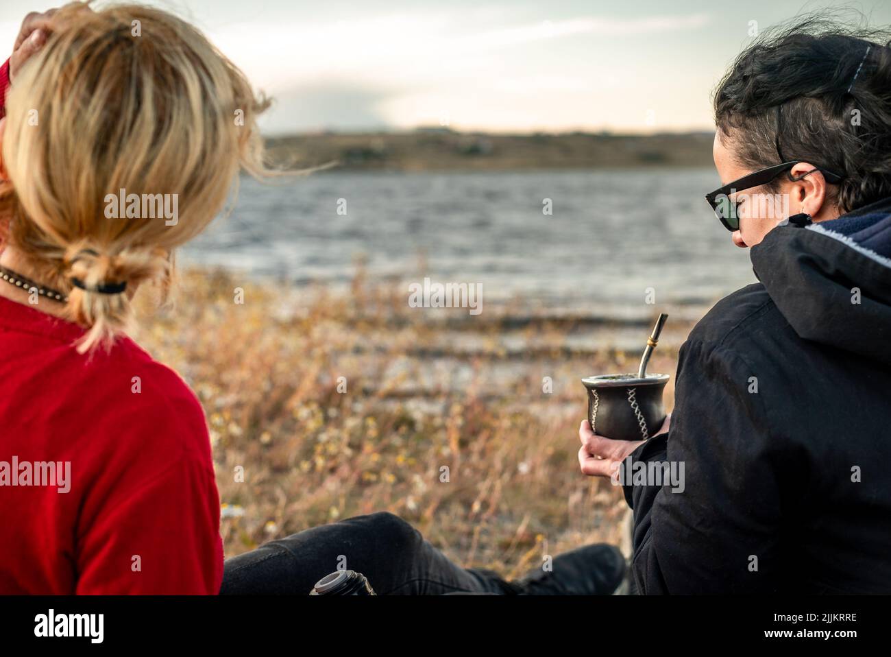 Die kaukasischen und hispanischen Weibchen sitzen gegen die Meereslandschaft und trinken Yerba Mate in Argentinien Stockfoto