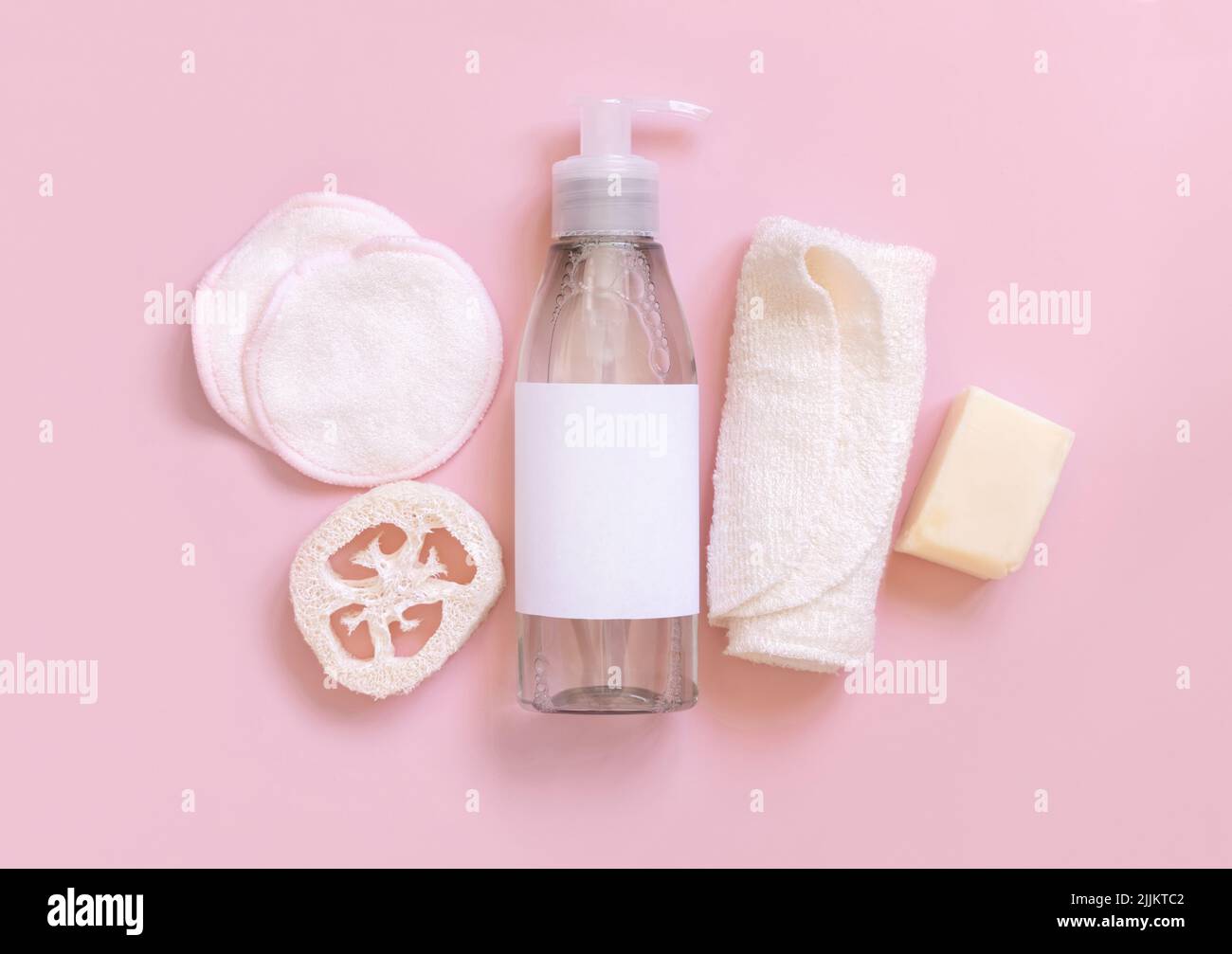 Eine Pumpe Kosmetikflasche und umweltfreundliches Hautpflegezubehör auf pinkfarbenem, flachem Lay, Kopierraum. Draufsicht auf natürliche Schönheitsprodukte für Haar und Haut ca. Stockfoto