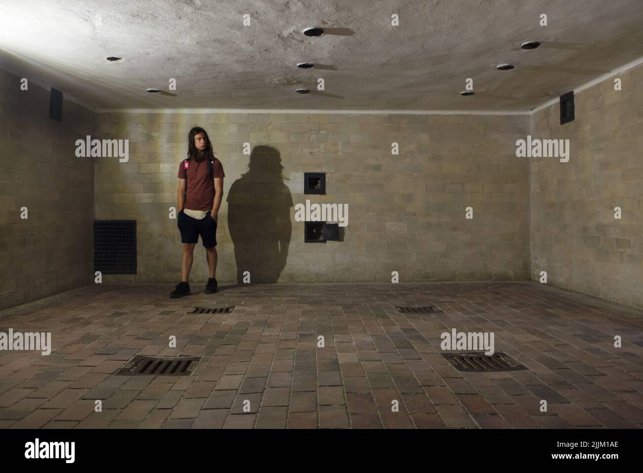 Junger Besucher in der Gaskammer des großen Krematoriums (Baracke X) im ehemaligen Konzentrationslager Dachau, heute KZ-Gedenkstätte Dachau in Dachau bei München. Das große Krematorium wurde zwischen Mai 1942 und April 1943 errichtet. Das Krematorium diente sowohl als Tötungsanlage als auch zur Entfernung der Toten. Aber die als Brausebad (Duschbad) maskierte Gaskammer wurde nicht für Massenmorde genutzt. Überlebende haben ausgesagt, dass die SS hier jedoch einzelne Gefangene und kleine Gruppen mit Gift ermordet hat Stockfoto
