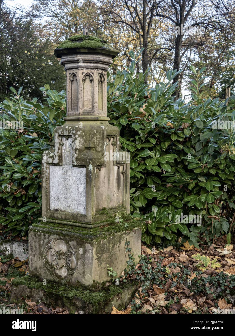 Eine vertikale Aufnahme eines moosigen Grabdenkmals auf einem Friedhof Stockfoto