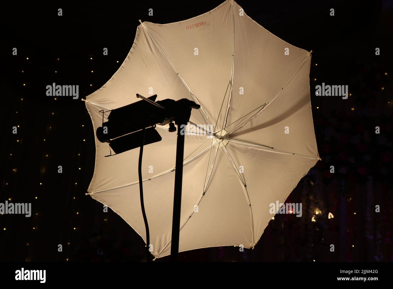 Blitzdiffusor mit einem Regenschirm und einer Halogenlampe. Studio-Diffusor mit weißem Reflektorschirm Stockfoto