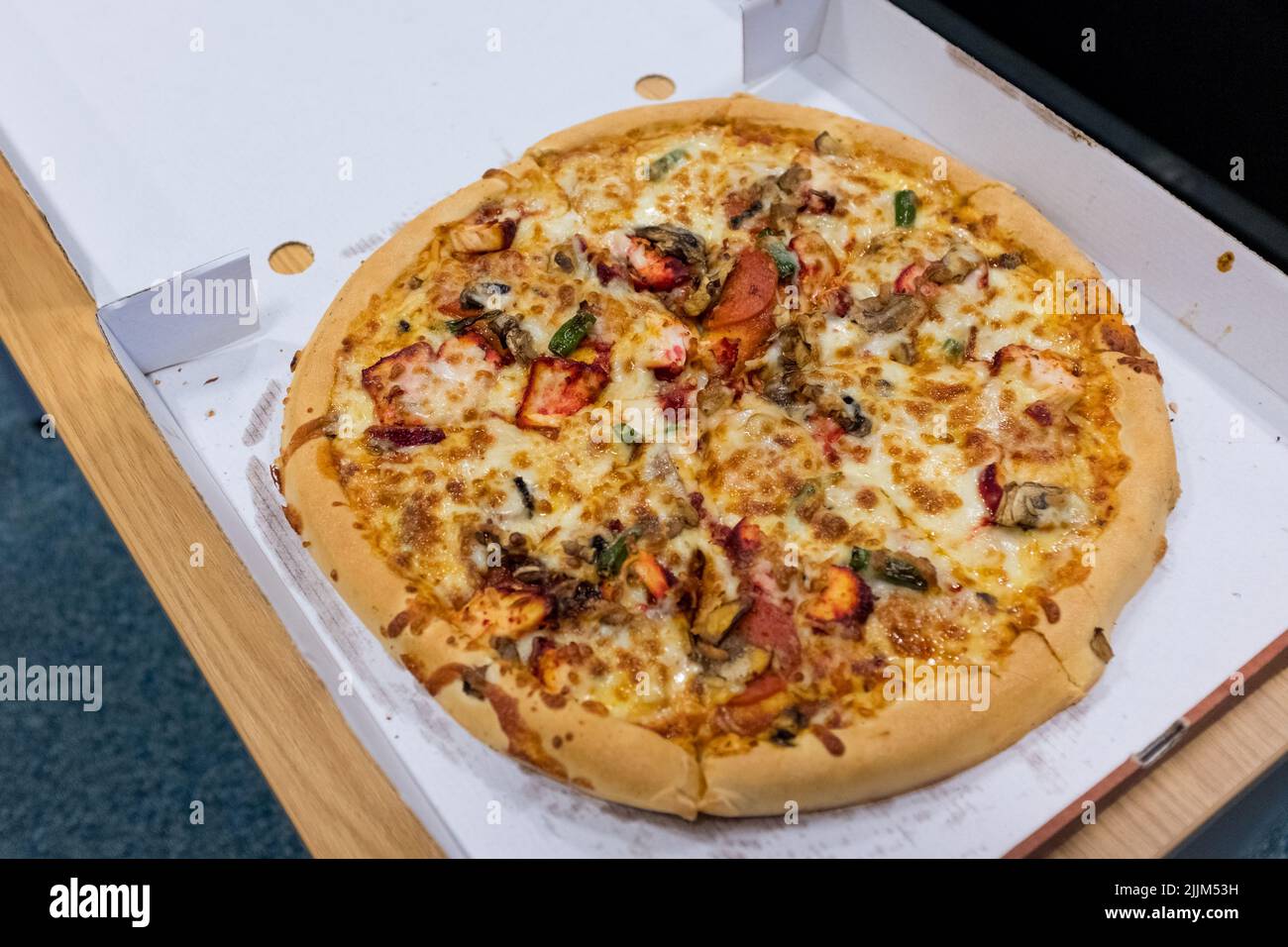 Newcastle England: 14.. Juli 2022: Riesige 14-Zoll-Pizza mit scharfem Chicken Tikka zum Mitnehmen. Sehr fettig in der Pizzakarton aus Pappe Stockfoto