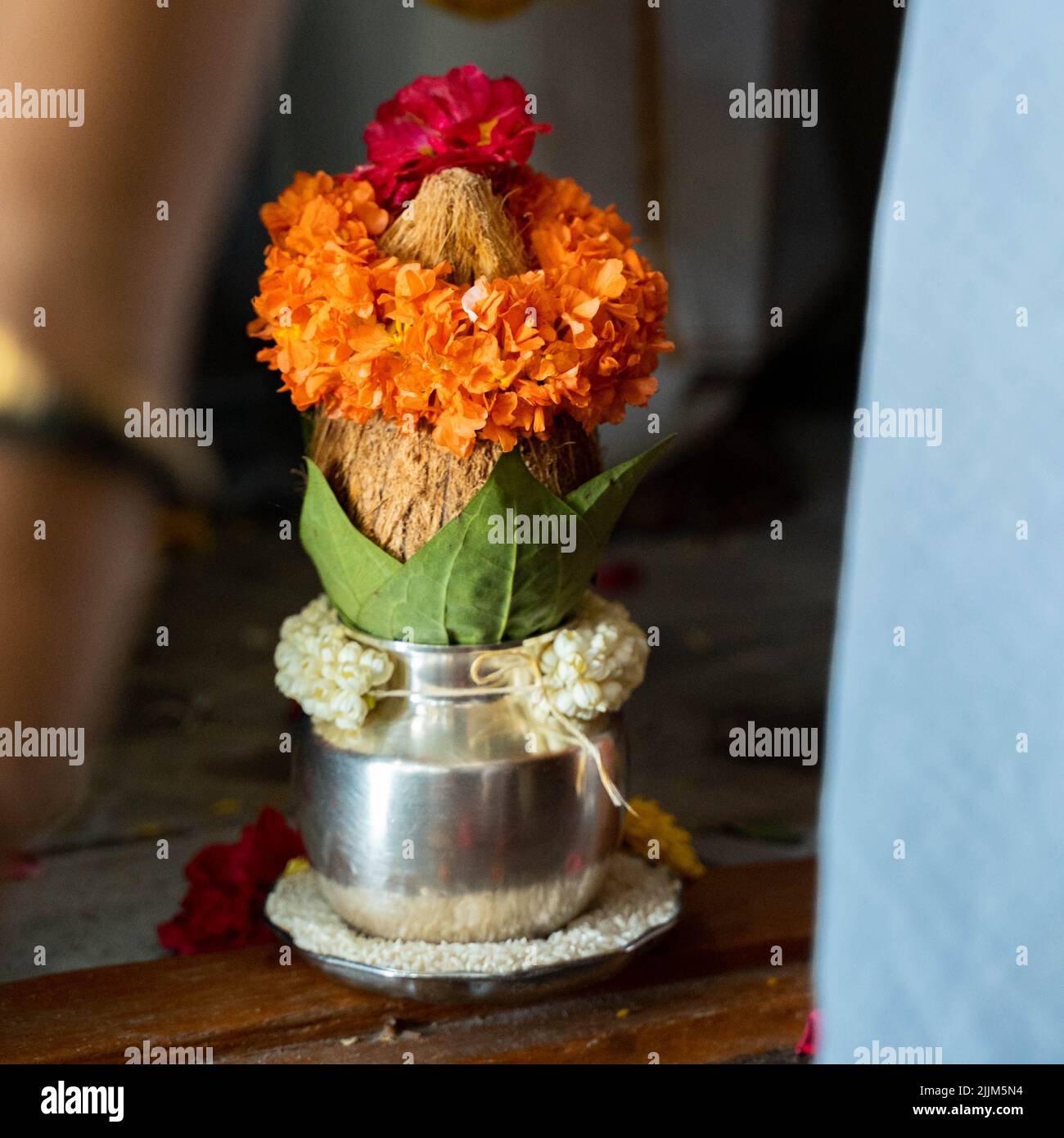 Ein flacher Fokus einer kupferfarbenen Kalasche mit Kokos- und Mangoblatt mit floraler Dekoration in hinduistischer Puja Stockfoto