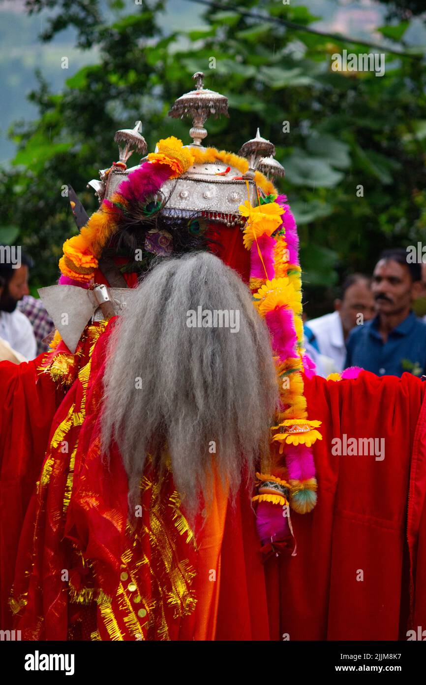 Eine vertikale Aufnahme eines Mannes in roten Kleidern, der in Rama, Indien, die indianischen Götter von Uttarakhand feiert Stockfoto