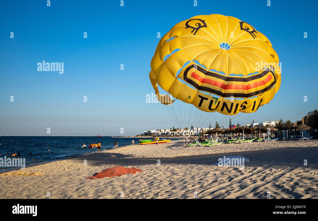 Ein gelber Fallschirm zum Parascending, der mit einem Lächeln und dem Wort „Tunesien“ geschmückt ist, ist am Strand in der Nähe von Kantaoui in Tunesien gebunden. Stockfoto