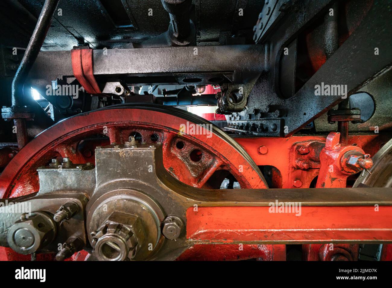 Nahaufnahme eines roten Ventilgetriebes einer alten Lokomotive mit fettiger und rostiger Dampfmaschine Stockfoto