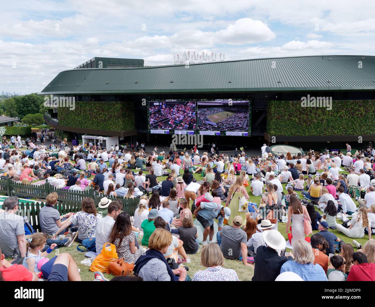 Wimbledon Tennis Championship. Massen sitzen auf dem Rasen auf dem Hügel vor dem Platz Nummer 1 und beobachten das Geschehen auf einer großen Leinwand. London. Stockfoto