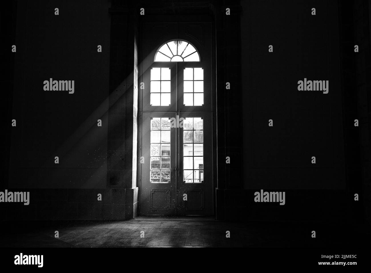Eine Graustufenaufnahme von Licht, das durch eine Tür hereinkommt Stockfoto