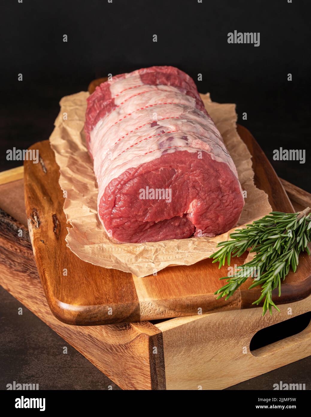 Food Fotografie von Rindfleisch, rohem Steak, Metzger, Filet, Fleisch, Holzbrett, Kräuter Stockfoto