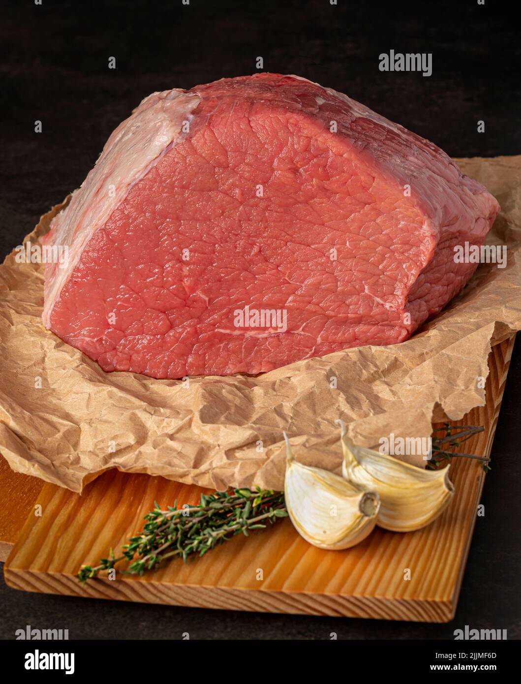 Food Fotografie von Rindfleisch, rohem Steak, Metzger, Filet, Fleisch, Holzbrett, Knoblauch, Kräuter Stockfoto