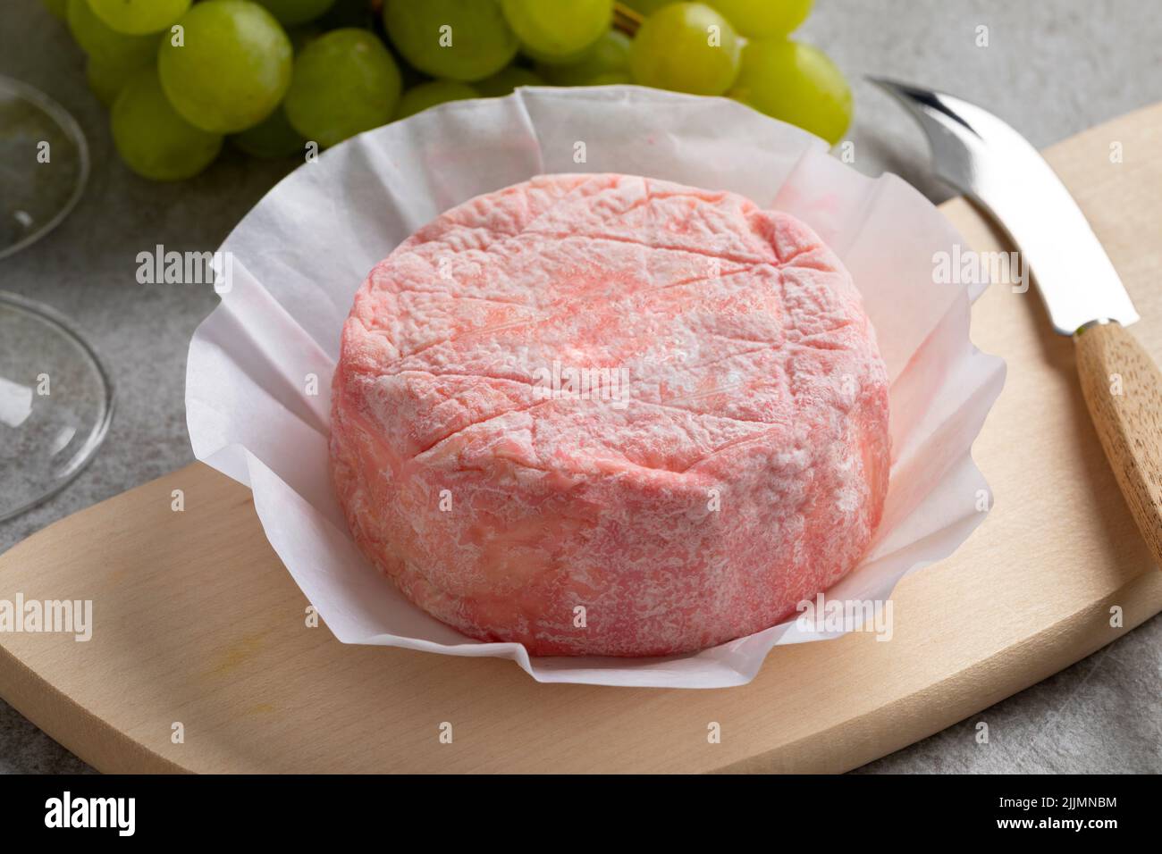 Le Rose, rosafarbener französischer Käse mit Kuhmilch und verfeinert mit Rosé-Champagner aus nächster Nähe auf einem Schneidebrett Stockfoto