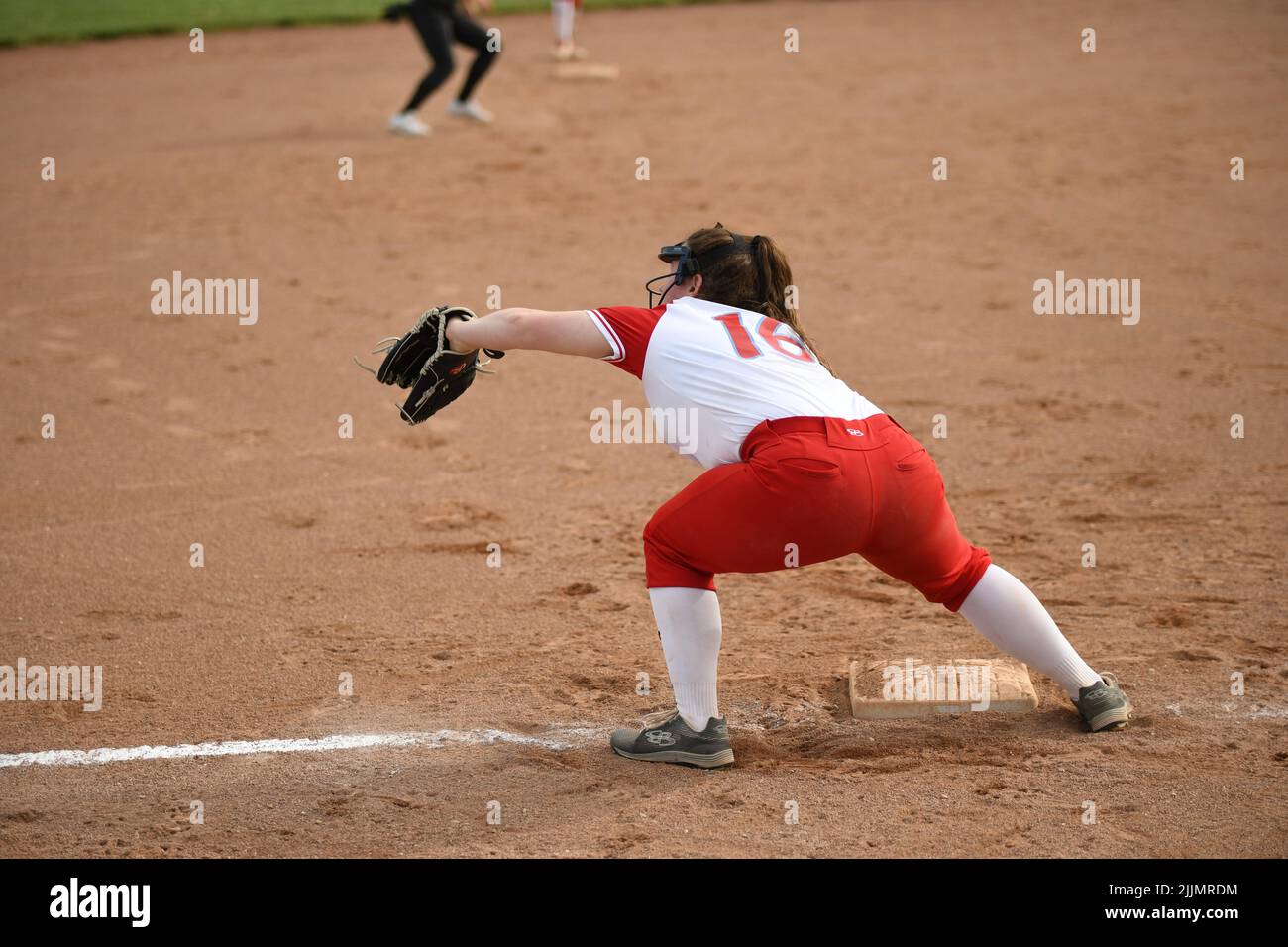 Ein Blick auf einen weiblichen Fänger, der Softball in rot-weißer Uniform spielt Stockfoto