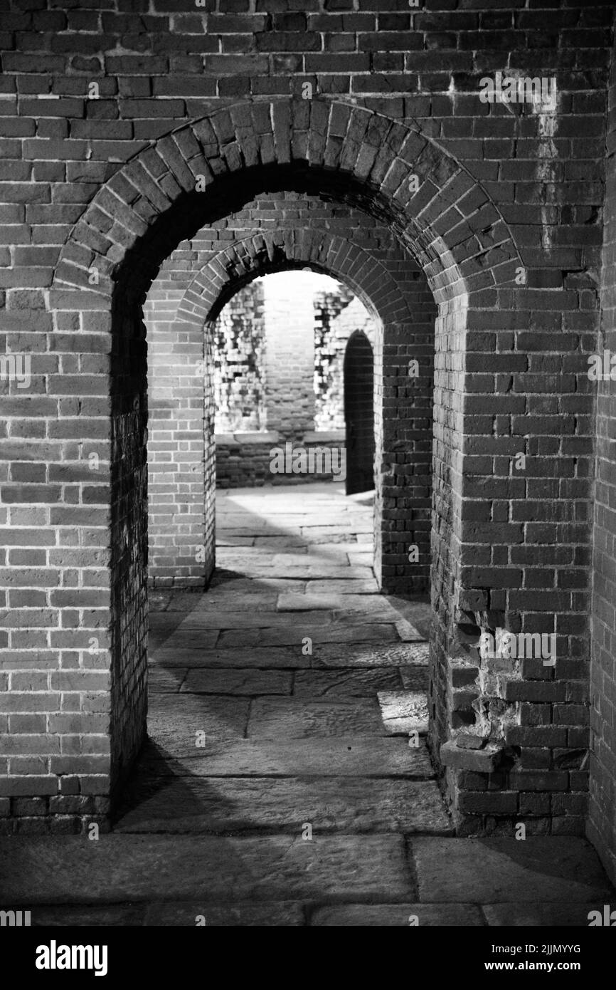 Eine wunderschöne Graustufenaufnahme von alten, mehrsteinigen Bogenstoren dahinter Stockfoto Eine wunderschöne Graustufenaufnahme von alten, mehrsteinigen Bogenstoren dahinter Stockfoto