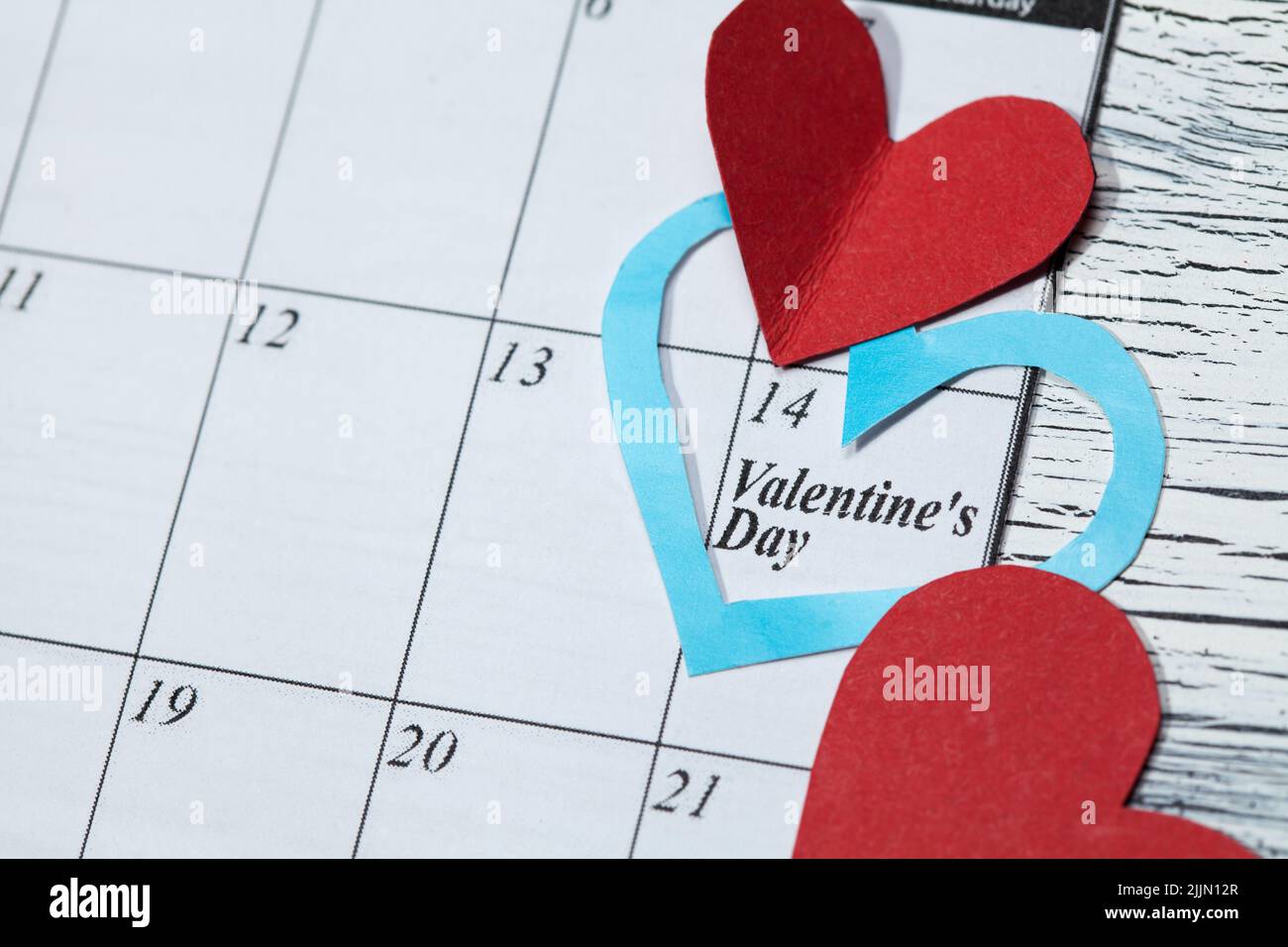 Eine Kalenderseite und Papierherzen am 14. Februar des Valentinstag Stockfoto